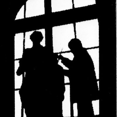 Zwei Silhouetten vor einem Sprossenfenster